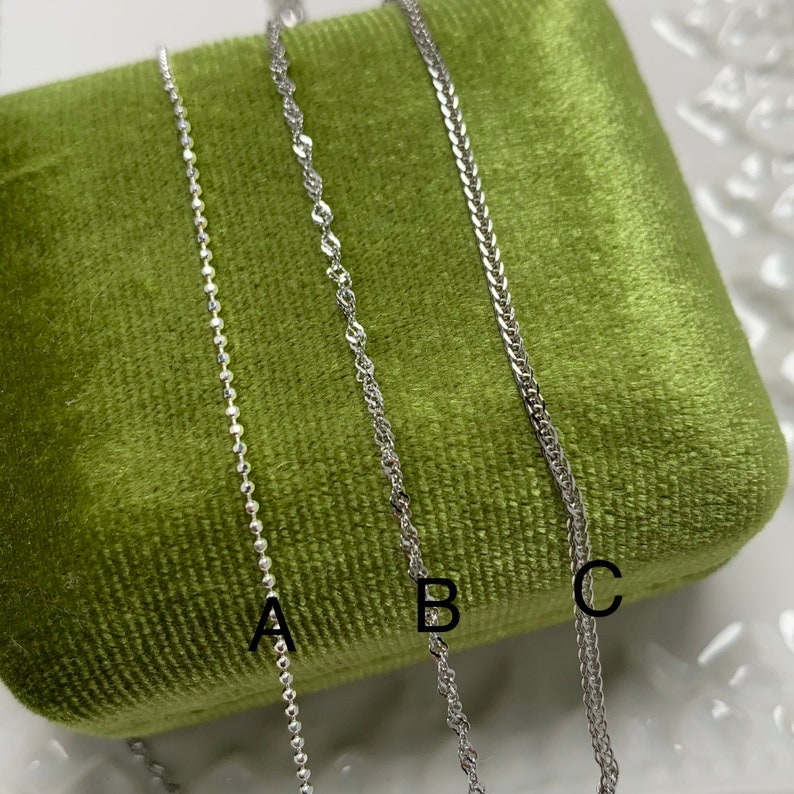 May include: Three silver chains of different styles, labelled A, B, and C, displayed on a green velvet surface.