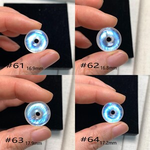 May include: Four iridescent moonstone beads, each with a hole in the centre. The beads are different sizes, ranging from 16.8 mm to 17.9 mm. The beads are labelled #61, #62, #63, and #64.