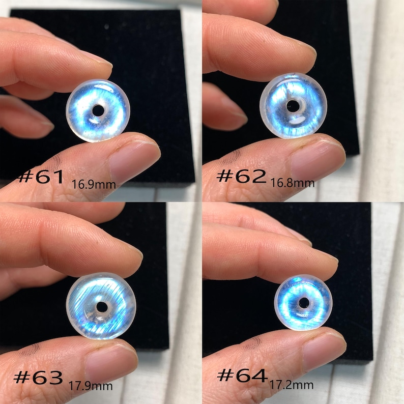 May include: Four iridescent moonstone beads, each with a hole in the centre. The beads are different sizes, ranging from 16.8 mm to 17.9 mm. The beads are labelled #61, #62, #63, and #64.