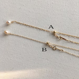 May include: Two gold chains with pearl accents. The chains are labelled A and B. Chain A has a small gold ball at the end and a clasp. Chain B has a small gold ball at the end and a clasp.