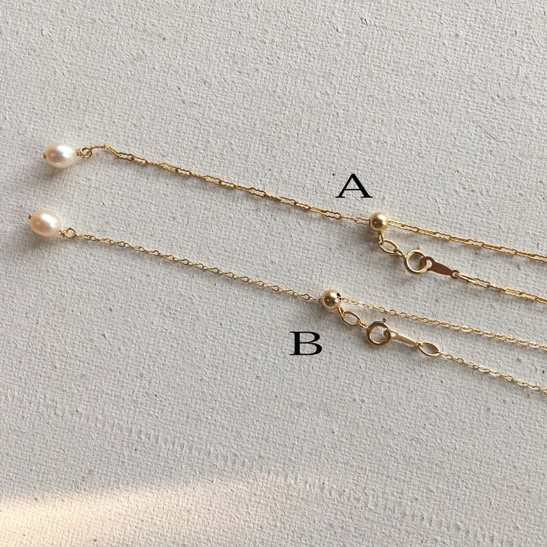 May include: Two gold chains with pearl accents. The chains are labelled A and B. Chain A has a small gold ball at the end and a clasp. Chain B has a small gold ball at the end and a clasp.