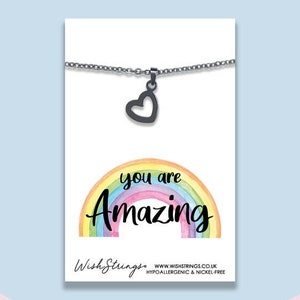 May include: A silver necklace with a black heart charm and a rainbow background with the text "You are amazing".