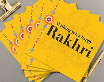 May include: A stack of yellow greeting cards with a decorative design and the text "Wishing you a happy Rakhri".