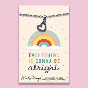 May include: A silver necklace with a black heart charm and a rainbow design. The necklace has the text "Everything is gonna be alright" on the card.