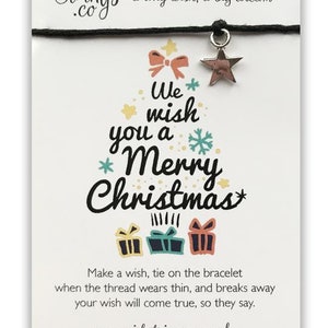 May include: A white card with a black string bracelet with a silver star charm. The card has a Christmas tree design with the text "We wish you a Merry Christmas". The card also includes the text "Make a wish, tie on the bracelet when the thread wears thin, and breaks away your wish will come true, so they say. www.wishstringsco.co.uk"