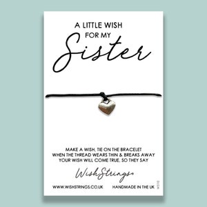 May include: A black string bracelet with a silver heart charm. The card reads "A Little Wish For My Sister" and "Make a wish, tie on the bracelet when the thread wears thin & breaks away your wish will come true, so they say." The card also includes the company name "Wish Strings" and website address "www.wishstrings.co.uk".