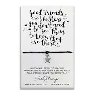 Op de afbeelding: Zwart koord armband met een zilveren ster bedel. De kaart die aan het armband is bevestigd, luidt "Good Friends are like stars * you don't need * to see them to know they are there *" en "Make a wish, tie on the bracelet when the thread wears thin & breaks away your wish will come true, so they say. Wish Strings. WWW.WISHSTRINGS.CO.UK HANDMADE IN THE UK"