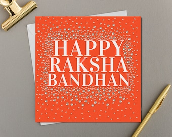 May include: A red card with white text that reads "Happy Raksha Bandhan". The card is covered in small silver glitter.