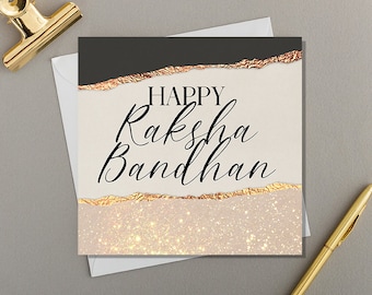 May include: A square greeting card featuring the text Happy Raksha Bandhan in black script and serif fonts. The design includes a dark gray top section, a cream middle, and a glittery gold bottom, separated by horizontal torn paper edges.