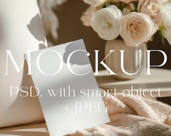 Puede incluir: Imagen de maqueta con una tarjeta blanca con la palabra «MOCKUP» en letras grandes. La tarjeta está apoyada contra una almohada color crema. Un jarrón de rosas y una manta doblada también están en la imagen. El texto «PSD. with smart object + JPEG» también es visible.