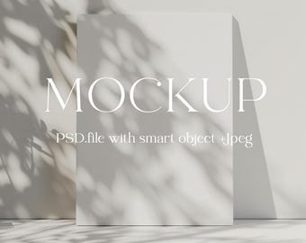 May include: A white mockup template with the word "MOCKUP" in a sans-serif font. The text "PSD.file with smart object +Jpeg" is below the word "MOCKUP". The template is on a white surface with shadows from a window.