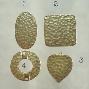 May include: Four gold-colored metal charms with a hammered texture. The shapes include an oval, a square, a heart, and a circle with a hole in the center. Each charm has a small hole for attaching to jewelry.