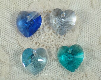 May include: Four heart-shaped crystal pendants in shades of blue and teal. Each pendant has a small hole at the top for stringing. The crystals are faceted, reflecting light and creating a sparkling effect.