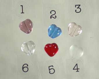 May include: A collection of heart-shaped beads in various colors, including pink, blue, clear, red, and white. Each bead is placed on a numbered, transparent sticker. The beads are made of a translucent material.