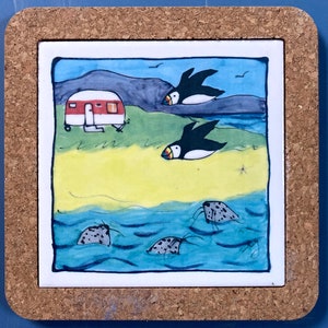 Könnte beinhalten: Ein Untersetzer aus Keramik mit einer skurrilen Illustration eines rot-weißen Wohnwagens, zwei schwarz-weißen Papageientauchern und drei grauen Robben in blauem Wasser. Der Hintergrund ist ein blauer Himmel mit einem grauen Berg und grünem Gras.