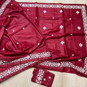 Op de afbeelding: Een dieprode textielset met ingewikkelde witte borduurpatronen. De set bevat een groot rechthoekig stuk, een kleiner vierkant stuk en een bijpassend rechthoekig stuk. De randen zijn versierd met een gedetailleerde witte rand en kwasten.