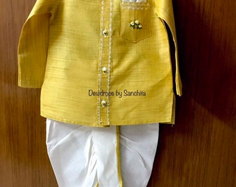 May include: A yellow kurta with white embroidery and a white pocket square. The kurta has a white trim and a button-up closure. The outfit is paired with a white dhoti with a yellow trim. The text "Dewdrops by Sanchita" is visible on the kurta.