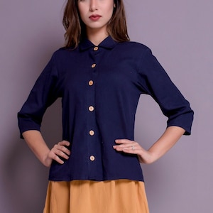 Pu&ograve; includere: Una camicia blu navy con bottoni, colletto e maniche lunghe abbinata a una gonna a trapezio giallo senape.