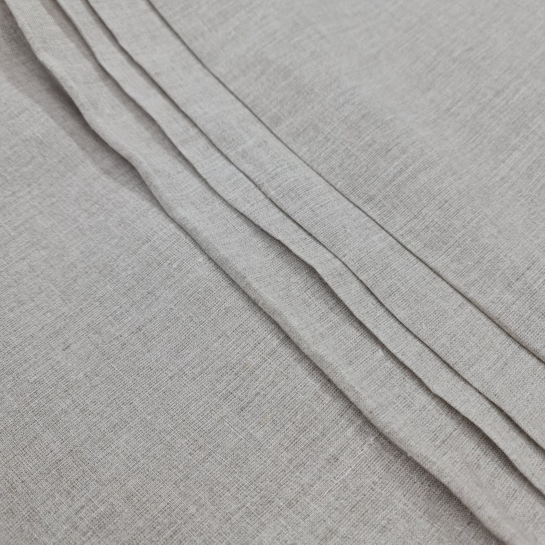 May include: Close-up of a gray fabric with a textured surface. The fabric is folded in a series of pleats, creating a subtle pattern.