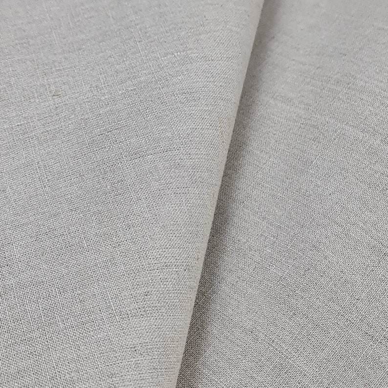 May include: Close-up of a light gray fabric with a woven texture. The fabric is folded in half, showing the smooth surface on one side and the textured surface on the other.