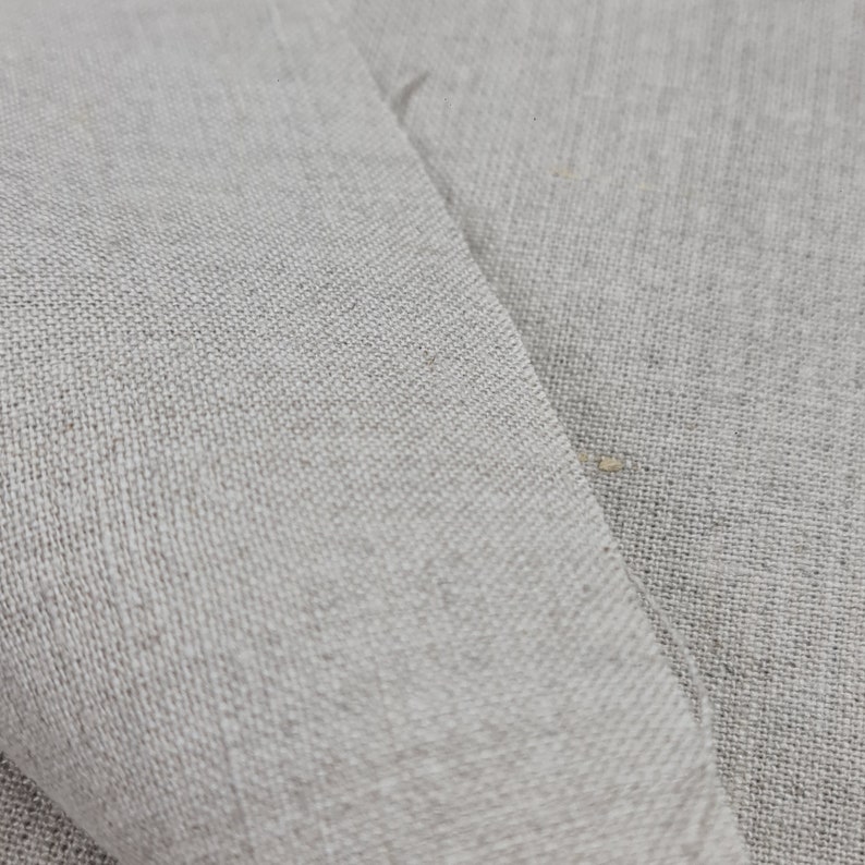 May include: Close-up of a light gray linen fabric with a woven texture.