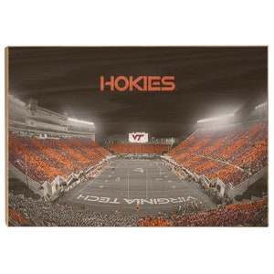 May include: A wood sign with a brown background and the words "HOKIES" in white text. The sign features a black and white photo of a packed football stadium with the words "VIRGINIA TECH" in white text on the field.