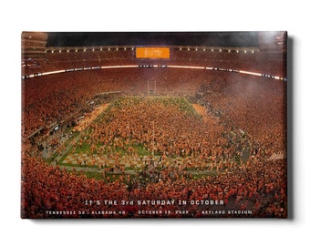 May include: A canvas print of a packed football stadium filled with orange-clad fans. The field is green with white yard lines. Text at the bottom reads "IT'S THE 3rd SATURDAY IN OCTOBER" and details the score of the Tennessee vs. Alabama game.