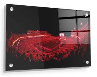 May include: A panoramic view of a packed football stadium at night. The stadium is filled with fans wearing red, and the field is lit up with bright lights. The words "Bulldogs" are visible on the field.