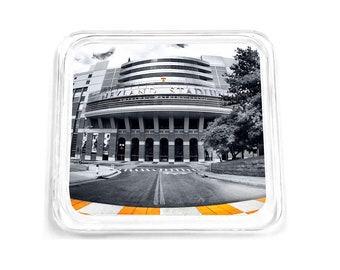 May include: A black and white photo of Neyland Stadium, home of the University of Tennessee Volunteers football team. The stadium is a large, brick structure with a large archway in the center. The photo is taken from a low angle, looking up at the stadium.