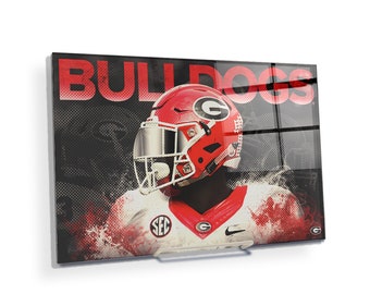 Puede incluir: Un casco de fútbol rojo y blanco con una máscara facial negra y una camiseta blanca y roja con el texto "SEC" y "G" en ella. El fondo es una imagen en blanco y negro con el texto "BULLDOGS" en rojo.