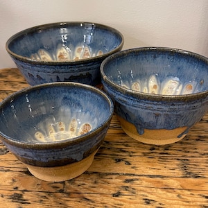 Peut inclure: Trois bols en céramique faits à la main. Les bols présentent un glaçage bleu foncé à l'extérieur et à l'intérieur, avec un motif plus clair et texturé à la base. Les bords sont bleu foncé et les bases sont non émaillées.