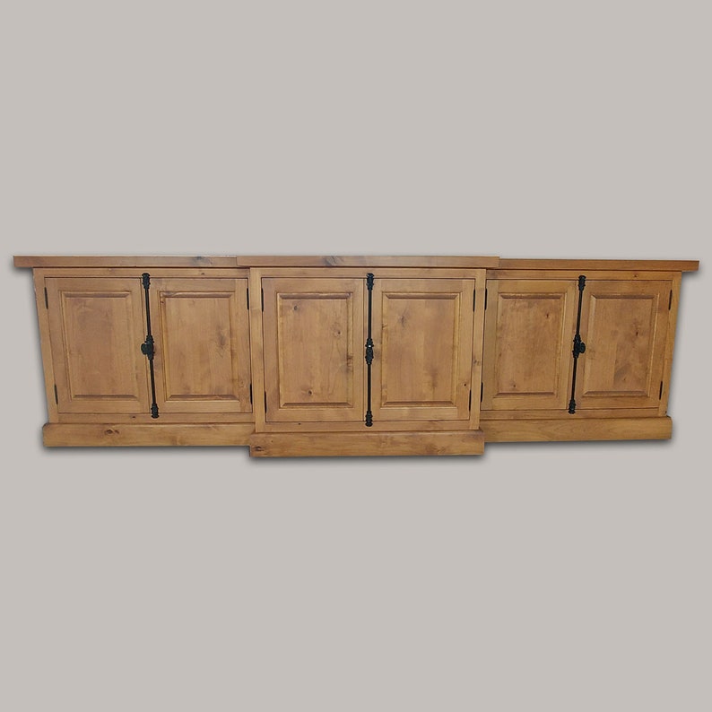 May include: A long, wooden cabinet with six doors and black metal hardware. The cabinet is made of light brown wood and has a rustic finish.