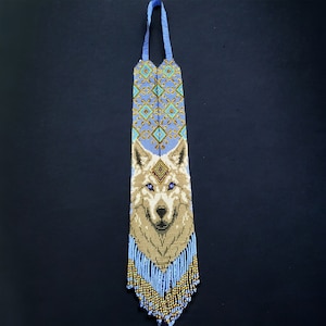 May include: A beaded wolf head pendant with a blue and gold geometric pattern. The pendant has a fringe of blue and gold beads.