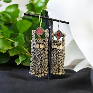 May include: A pair of silver dangle earrings with a red, green and blue stone design. The earrings have a chain tassel and are approximately 7.5 cm long.