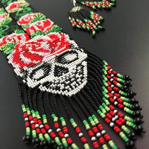 May include: A beaded necklace and earrings set with a skull design, red roses, and black, white, green, and red beads.