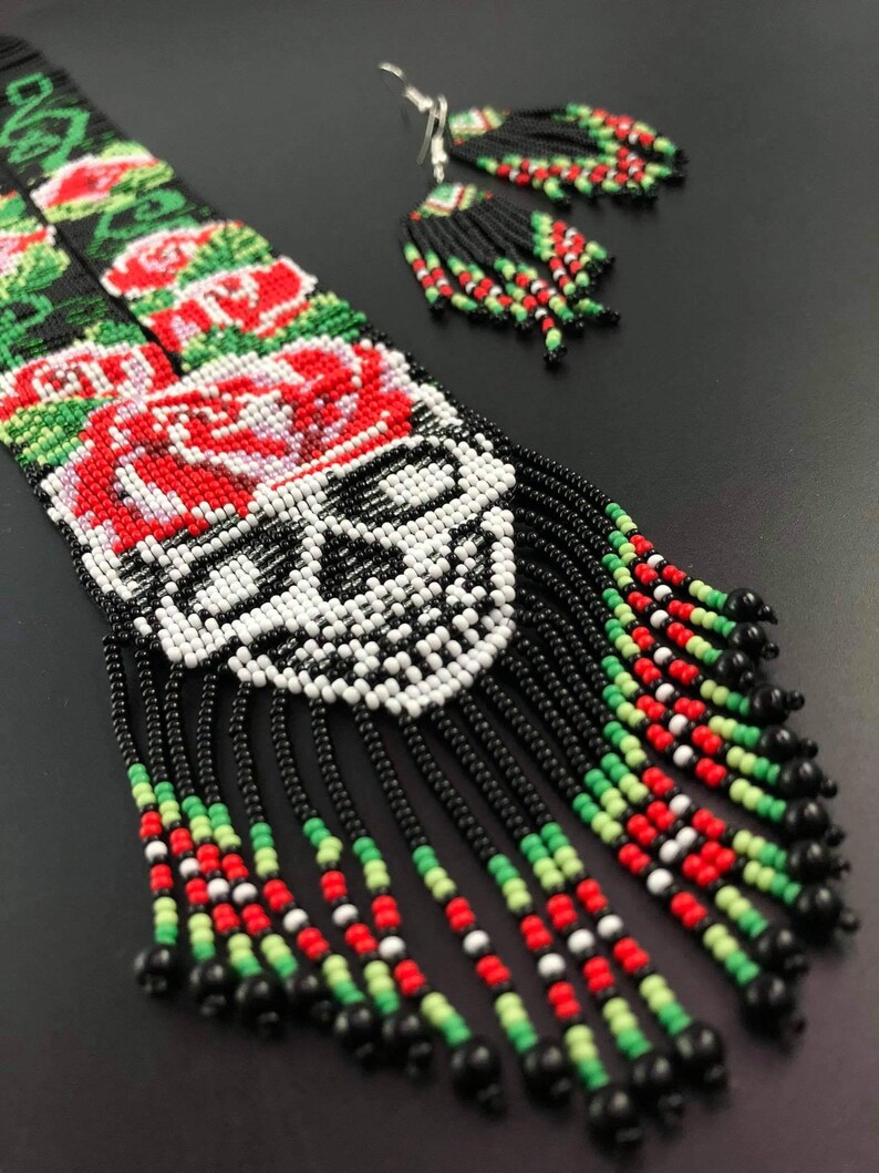 May include: A beaded necklace and earrings set with a skull design, red roses, and black, white, green, and red beads.