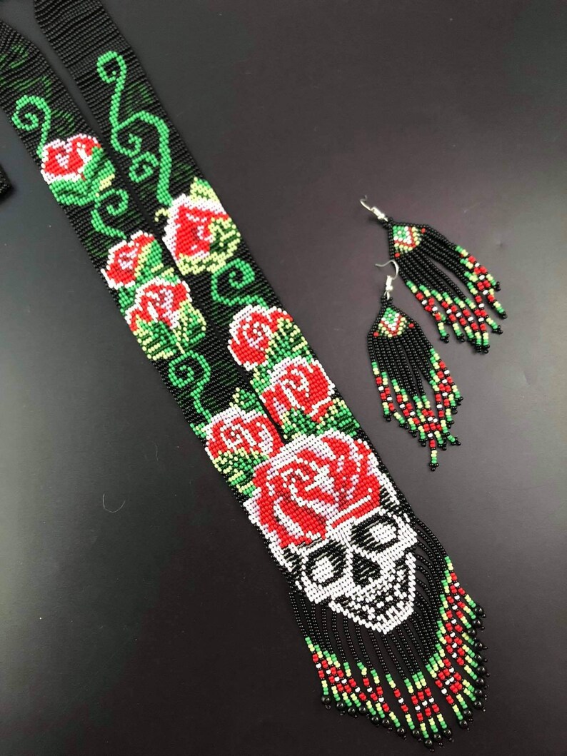 May include: A black beaded necklace with a skull and red roses, and matching beaded earrings with black tassels.