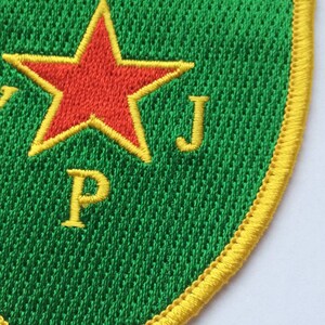 May include: A green and yellow embroidered patch with a red star and the letters "P" and "J".