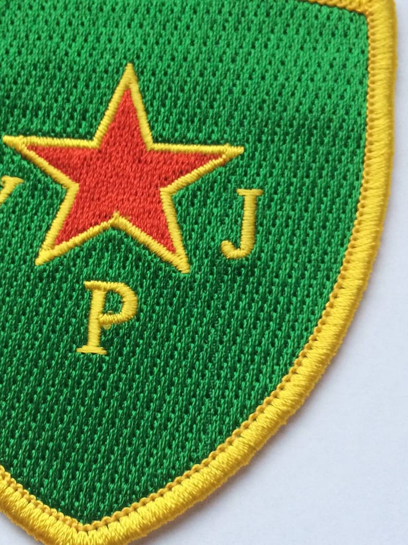 May include: A green and yellow embroidered patch with a red star and the letters "P" and "J".