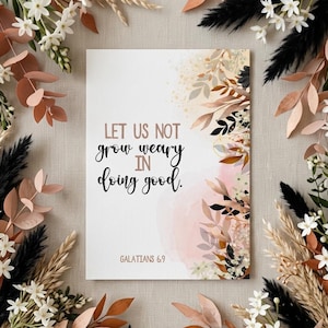 Puede incluir: Una impresión rectangular con el texto "LET US NOT grow weary IN doing good." rodeada de arreglos florales. La impresión tiene una paleta de colores suaves y neutros con acentos de marrón, negro y blanco. El texto está en una fuente manuscrita.