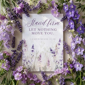 May include: A floral arrangement featuring a card with the text "Stand firm, Let nothing move you. 1 Corinthians 15:58." The card is surrounded by various purple flowers, including lavender and delphiniums, creating a serene and inspirational composition.