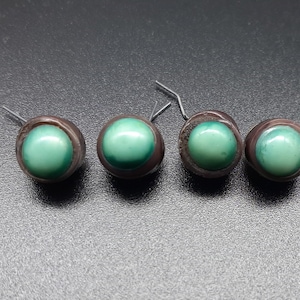 May include: Four green and brown round buttons with a metal loop on the back.
