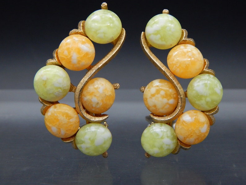 May include: A pair of gold tone clip-on earrings with a swirl design and orange and green marbled beads.