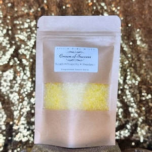 May include: A brown paper pouch with a label that reads "Little Gray Witch Crown of Success Wealth, Prosperity, Abundance Fragranced Epsom Salts". The pouch contains yellow bath salts.