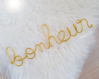 Word "happiness" in golden thread wall decoration