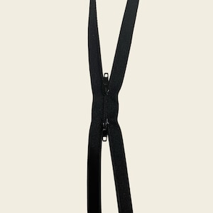 May include: A black two-way zipper featuring two matching black sliders on a continuous black fabric tape. The zipper teeth are interlocked in the center, with the top and bottom sections of the tape extending outwards in a V-shape.