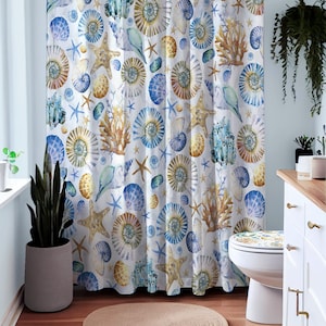 May include: A white shower curtain with a blue and brown seashell and starfish pattern. The shower curtain is hanging in a bathroom with a white toilet and a white vanity.