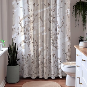 May include: A beige shower curtain with a brown floral and dragonfly pattern. The curtain is hung in a bathroom with a white toilet and a wooden cabinet.