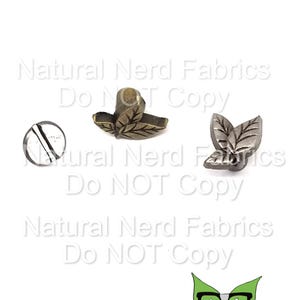 May include: Two metal leaf-shaped embellishments, one in gold and one in silver. The embellishments are about 1 inch in size and have a raised design. The embellishments are perfect for adding a touch of elegance to any project.