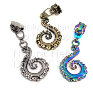 Könnte beinhalten: Drei Reißverschluss-Zipper in Form eines Kraken-Tentakels. Die Reißverschluss-Zipper sind in Silber, Bronze und schillerndem Regenbogenfarben.